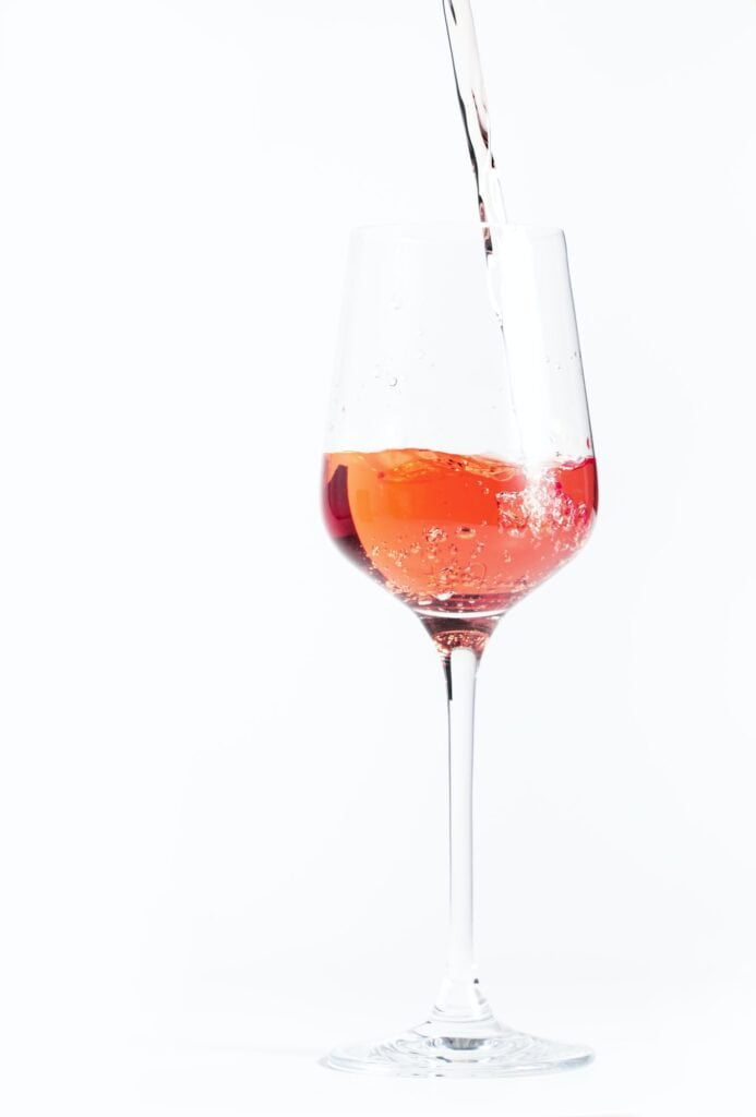 Rose wine pouring out of the bottle, white bakcground. Rosado, rosato or blush wine